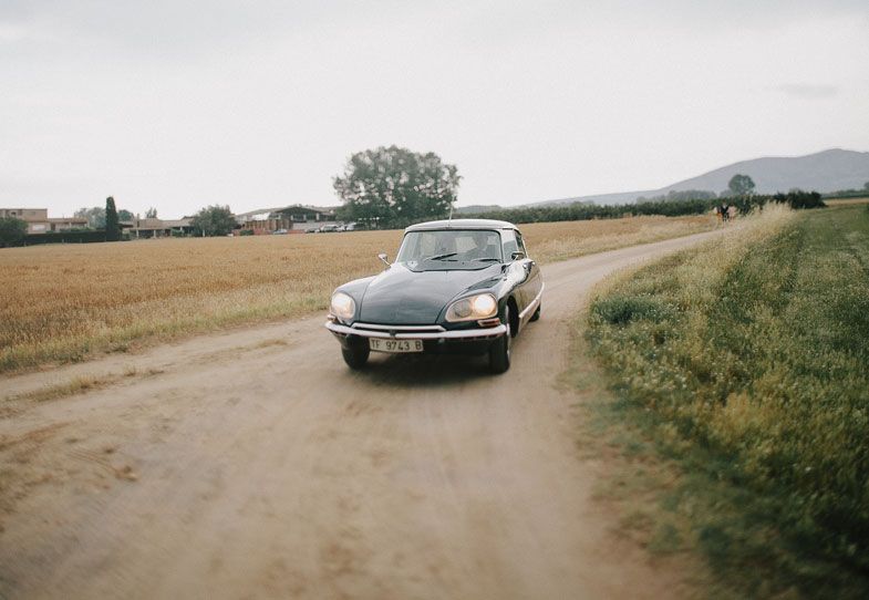 Classic Citroen DS driving down a rural country road.