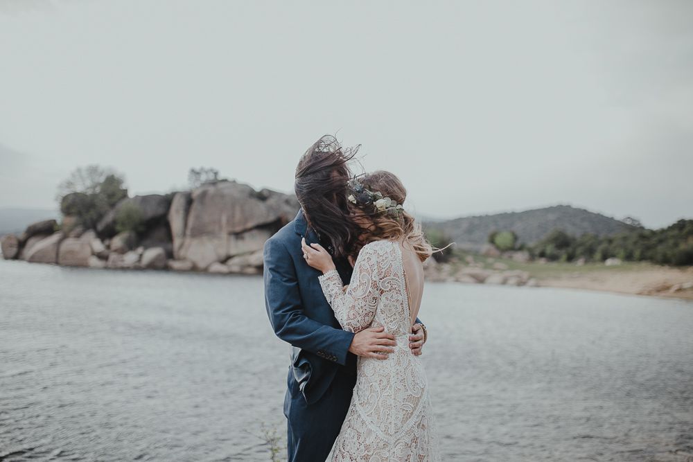 Intimate wedding photography on misty lakeshore with rocky landscape.