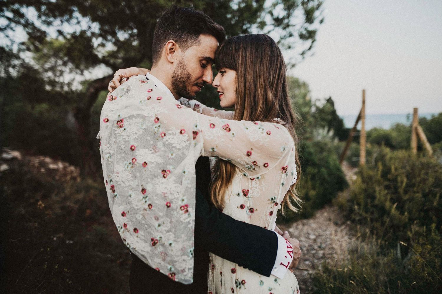 A couple shares an intimate moment on a mountain trail during sunset.
