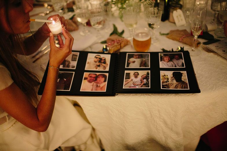 Someone looking through a photo album of wedding memories on a white tablecloth.