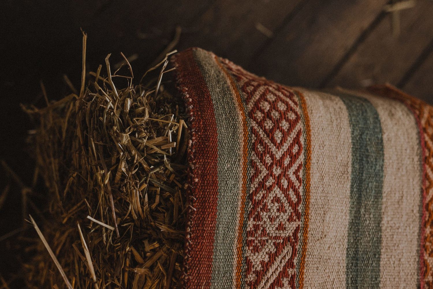 Close-up of a traditional patterned textile with hay or straw in rustic setting.