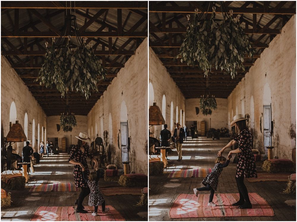 Interior of a rustic hall with exposed beams and hanging greenery decorations.