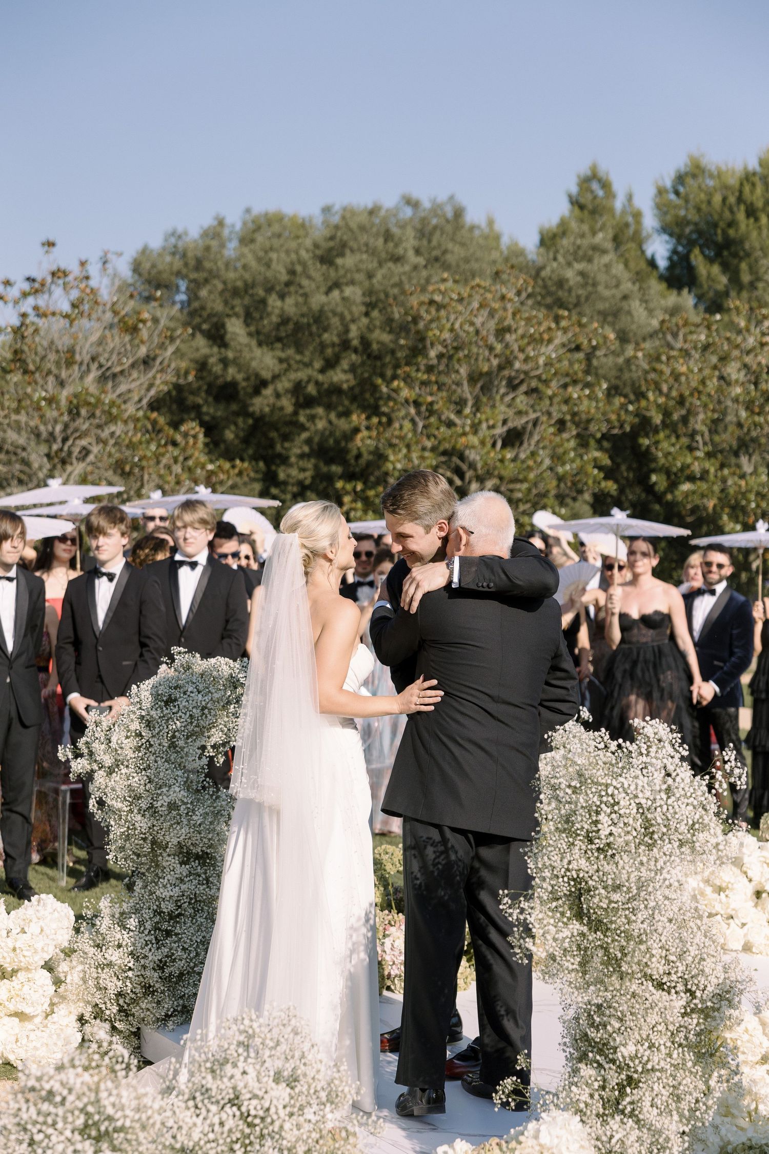 Wedding ceremony in progress with white floral arrangements and baby's breath decorating the aisle.