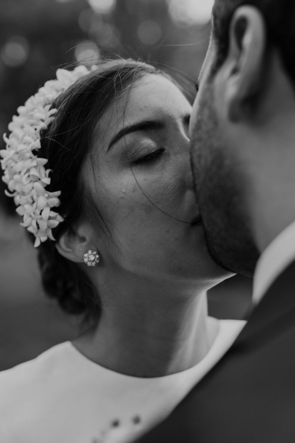 Intimate black and white portrait of romantic wedding moment with floral hair accessory.