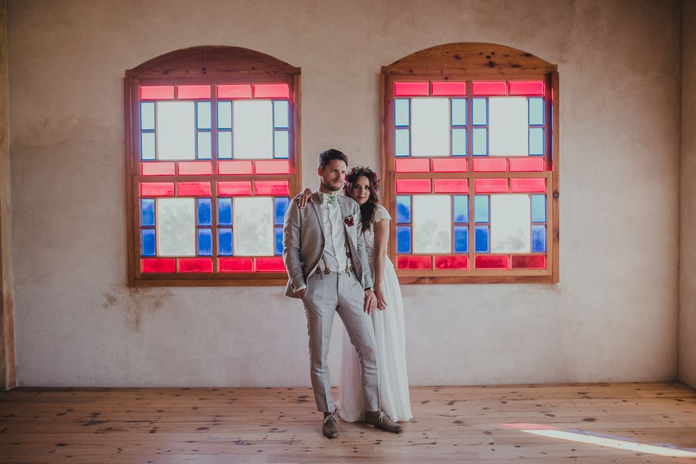 Elegant wedding couple poses in front of windows with red geometric designs.
