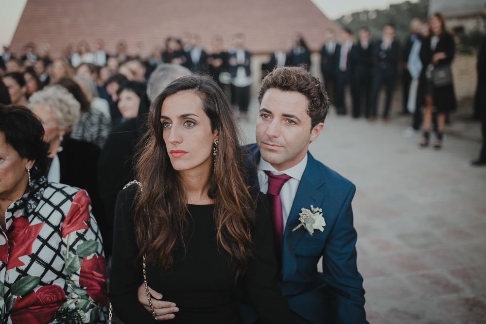 Wedding guests in formal attire at outdoor reception.