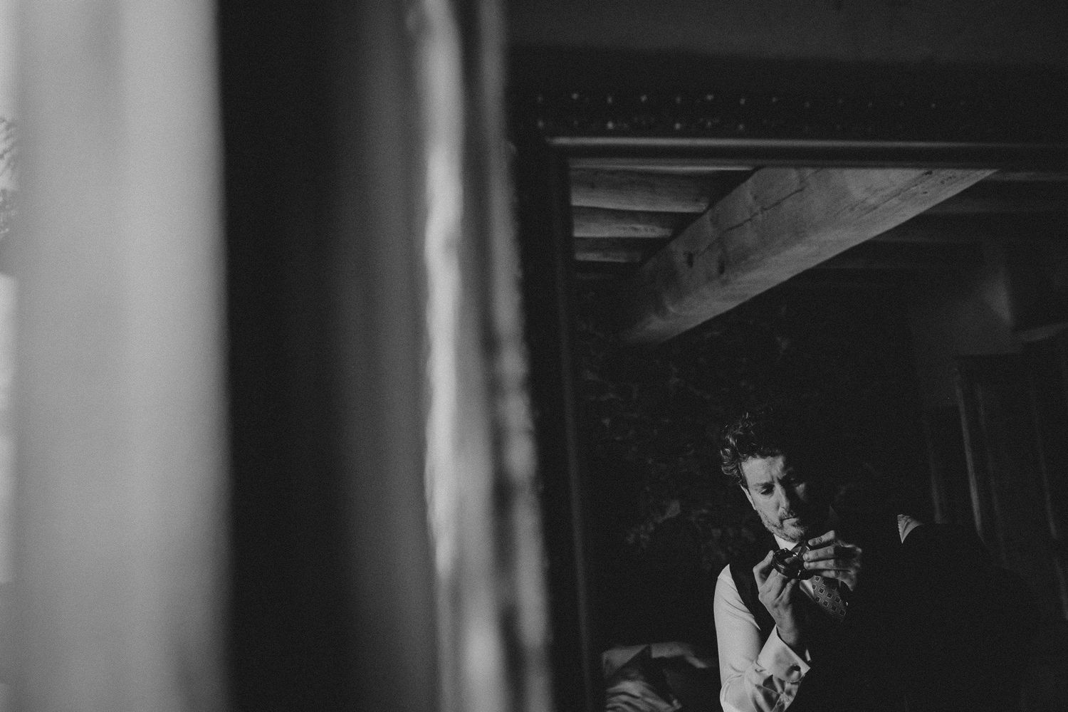 A black and white photo of someone using a camera in a dark interior space.