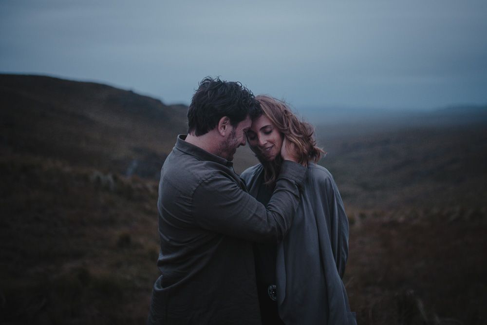 Intimate black and white portrait of couple embracing in mountain landscape.