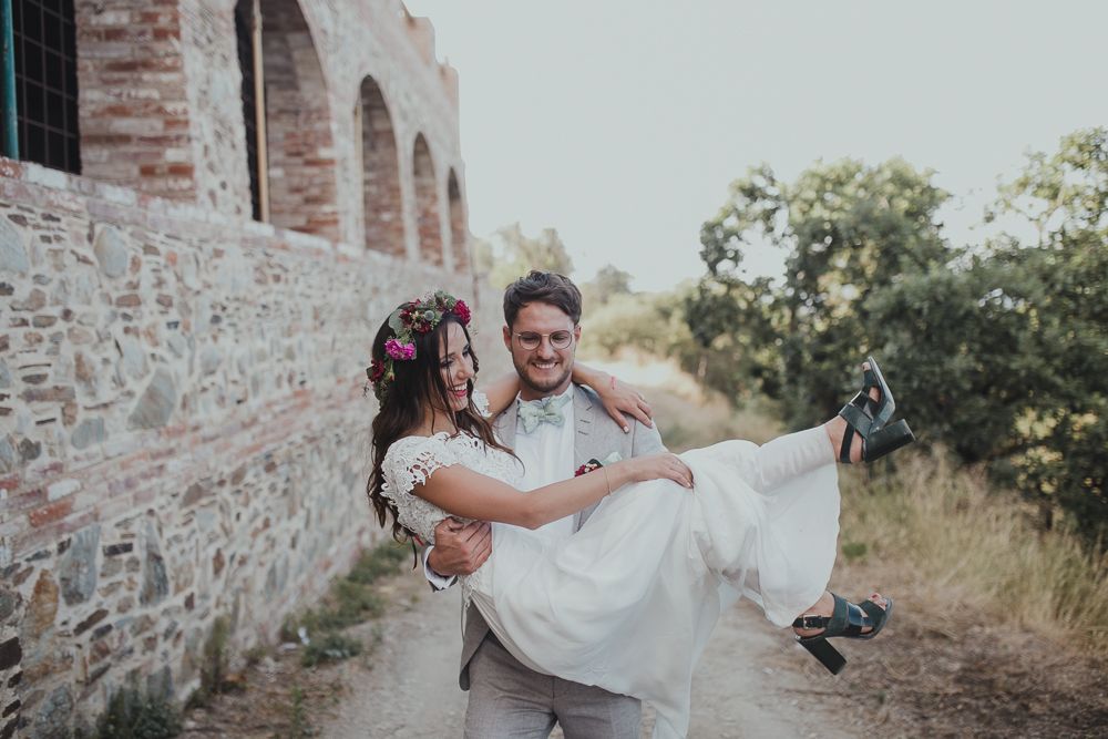A romantic bridal carry pose in front of a rustic stone building.