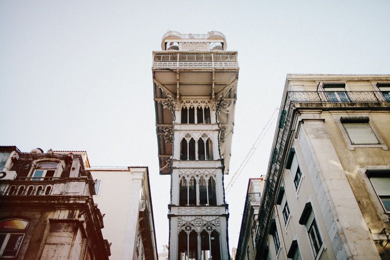 Santa Justa Lift tower rising between buildings in Lisbon's historic district.