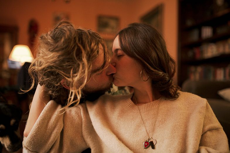 Tender moment shared between two people in warm lighting with bookshelves in background.