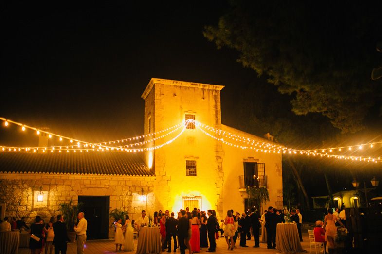 Stone building illuminated by string lights during evening wedding reception.