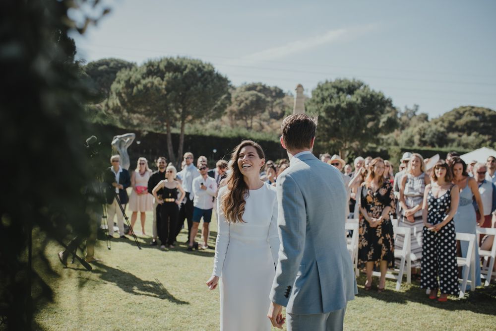 A couple sharing a joyful moment during their outdoor wedding ceremony with guests in the background.