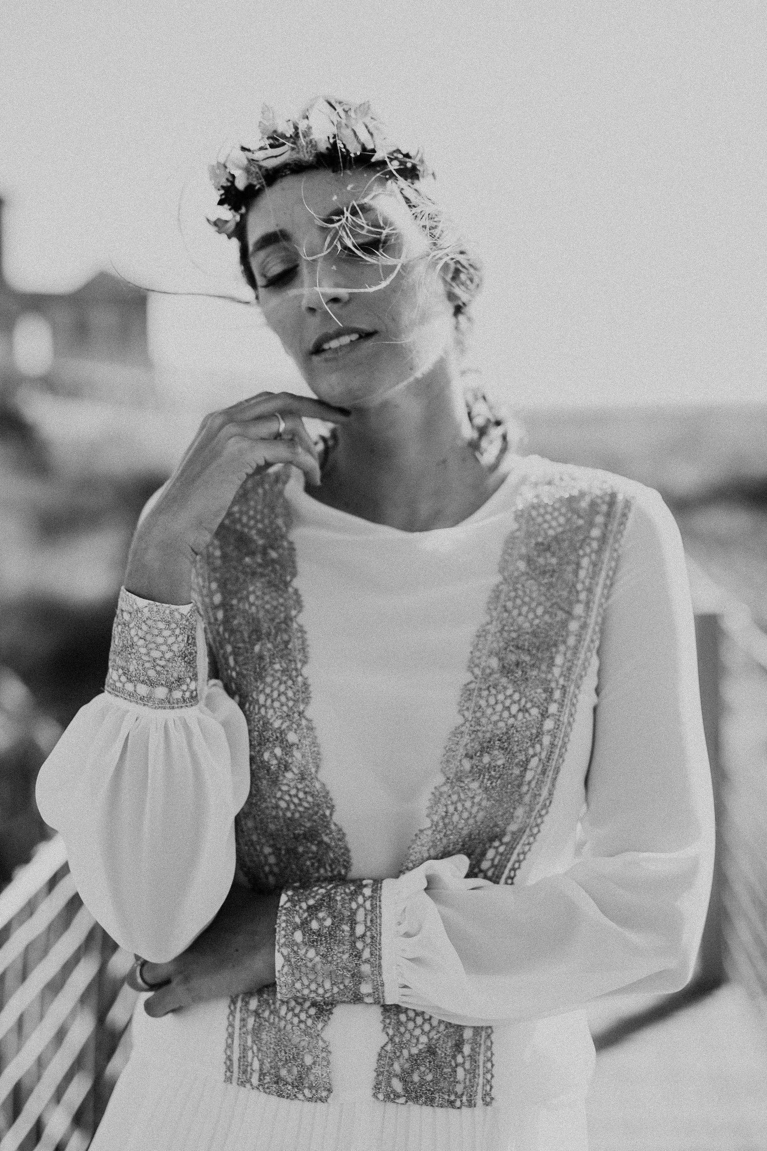 A dreamy portrait of someone wearing a white dress and floral crown in soft black and white.