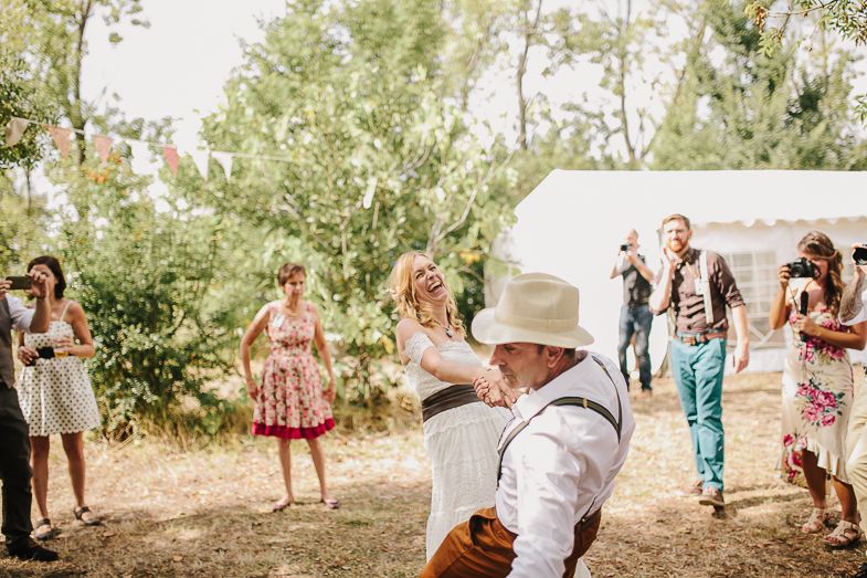 Wedding guests dancing and celebrating at an outdoor rustic-themed reception.