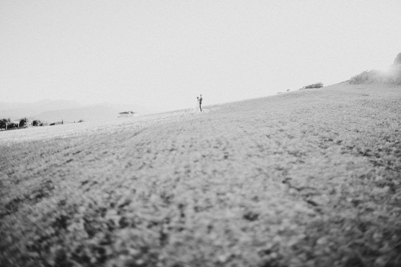 A lone figure stands on a distant hillside against an overcast sky.