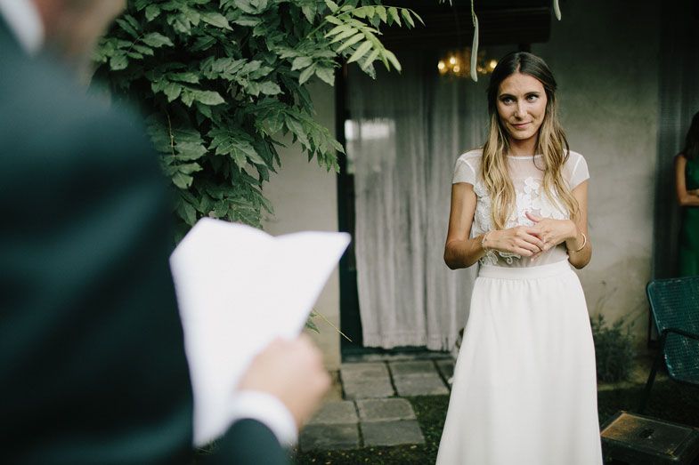 A garden wedding scene with someone in a white dress standing on stone pavers.