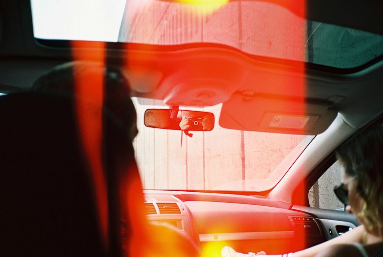 Interior car shot with red-tinted lighting and rearview mirror in focus.