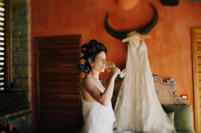 Getting ready scene with a white wedding dress hanging on orange wall with bull horns.