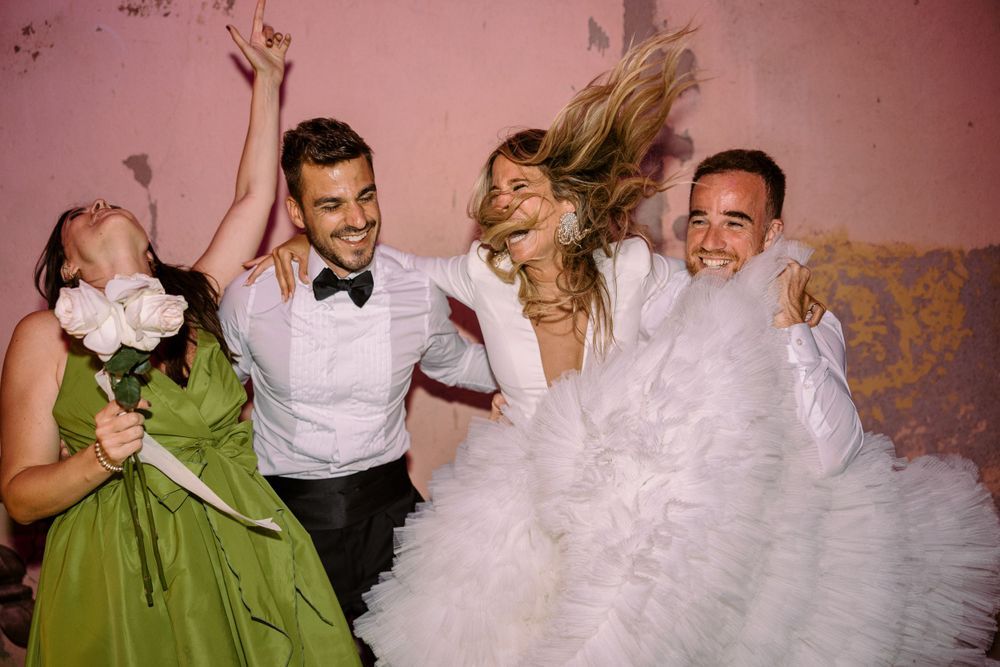 Wedding celebration with guests dancing and enjoying festivities in a pink-tinted room.