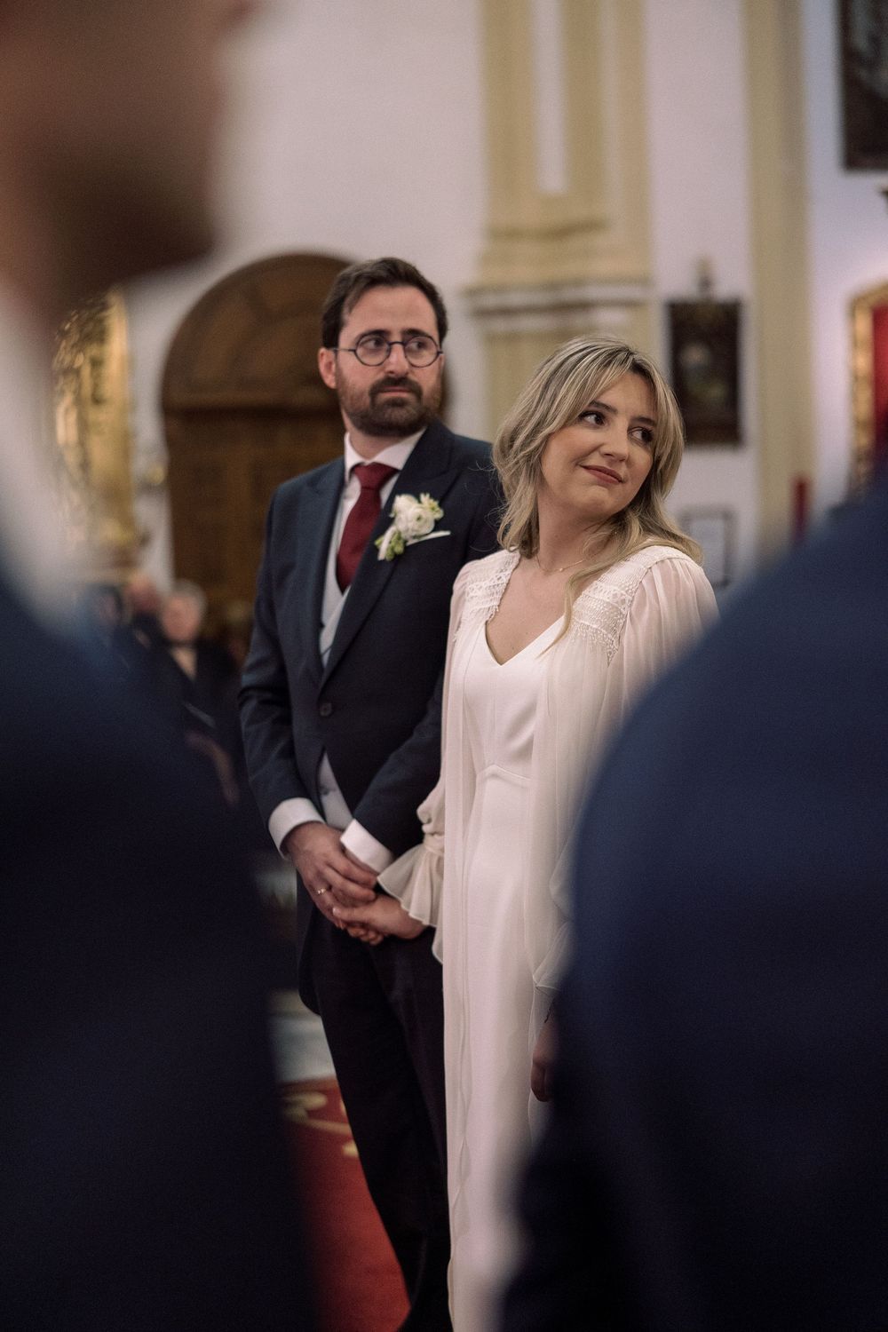 A couple stands together during their wedding ceremony in an elegant church setting.