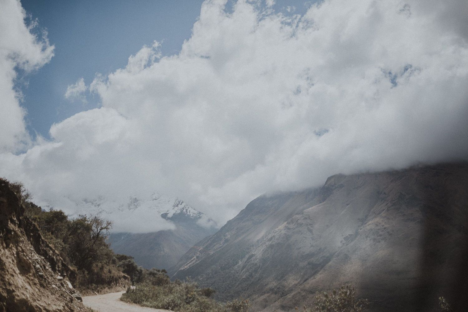 Misty mountain valley with dramatic clouds rolling through steep rocky terrain.