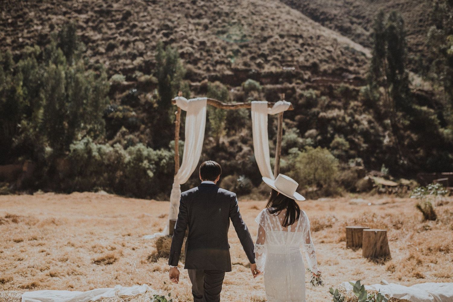 Wedding arch with flowing white fabric against a desert mountain landscape.