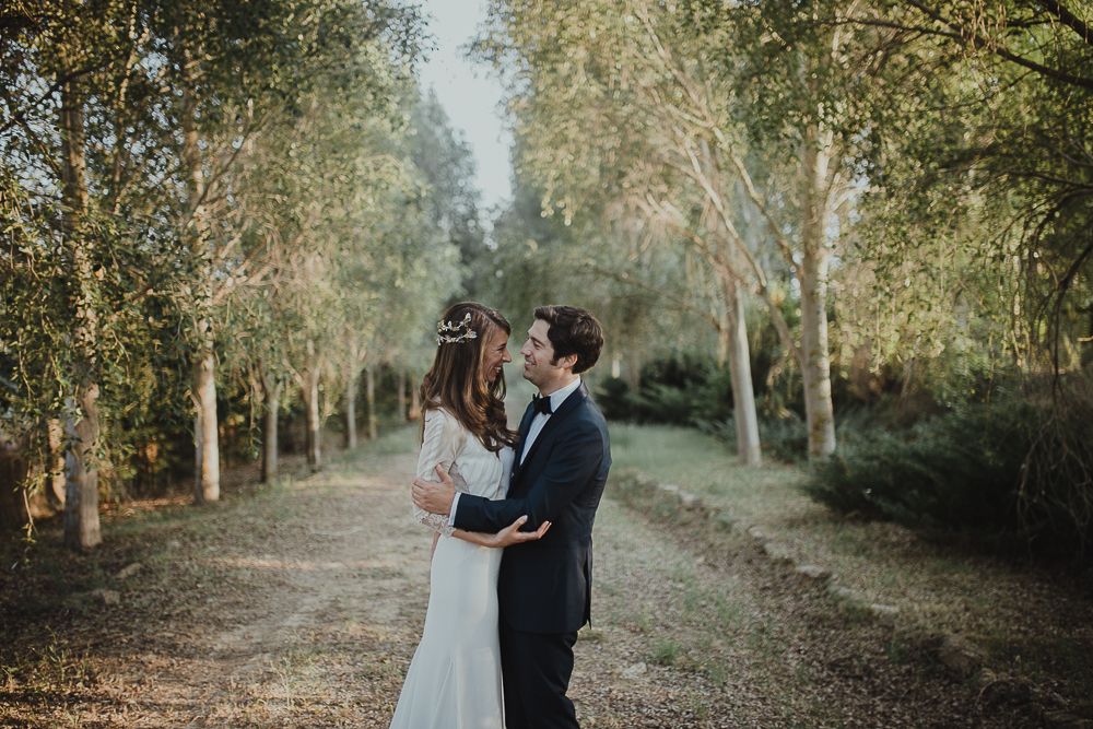 Romantic moment between couple on a tree-lined path during golden hour.