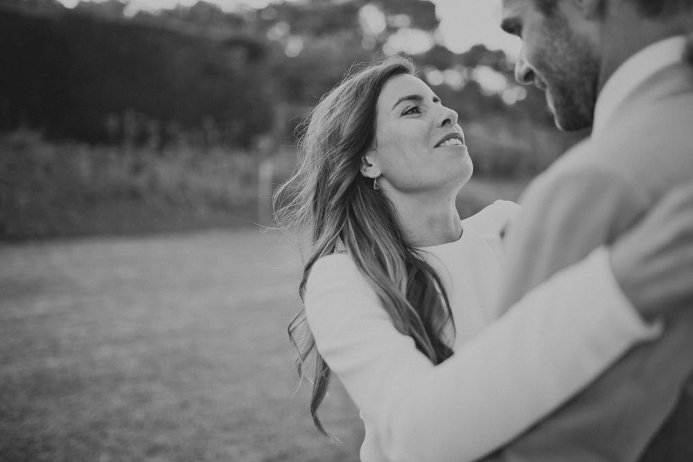 Black and white candid shot of a joyful couple dancing outdoors.