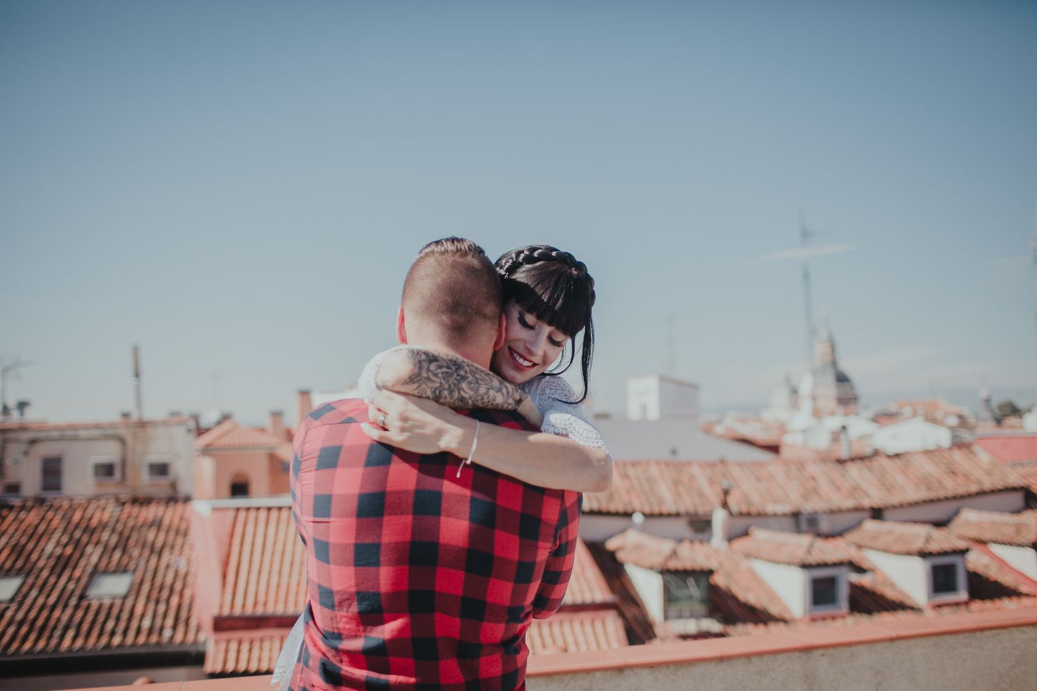 A tender moment captured on a European rooftop with traditional architecture in the background.