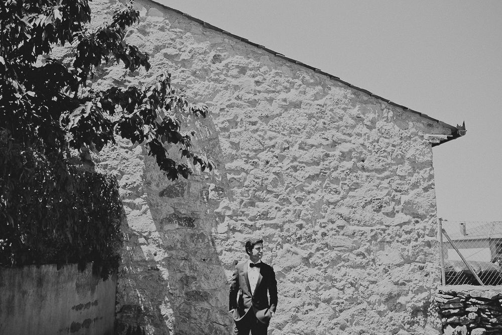 Black and white portrait against textured stone wall in natural lighting.