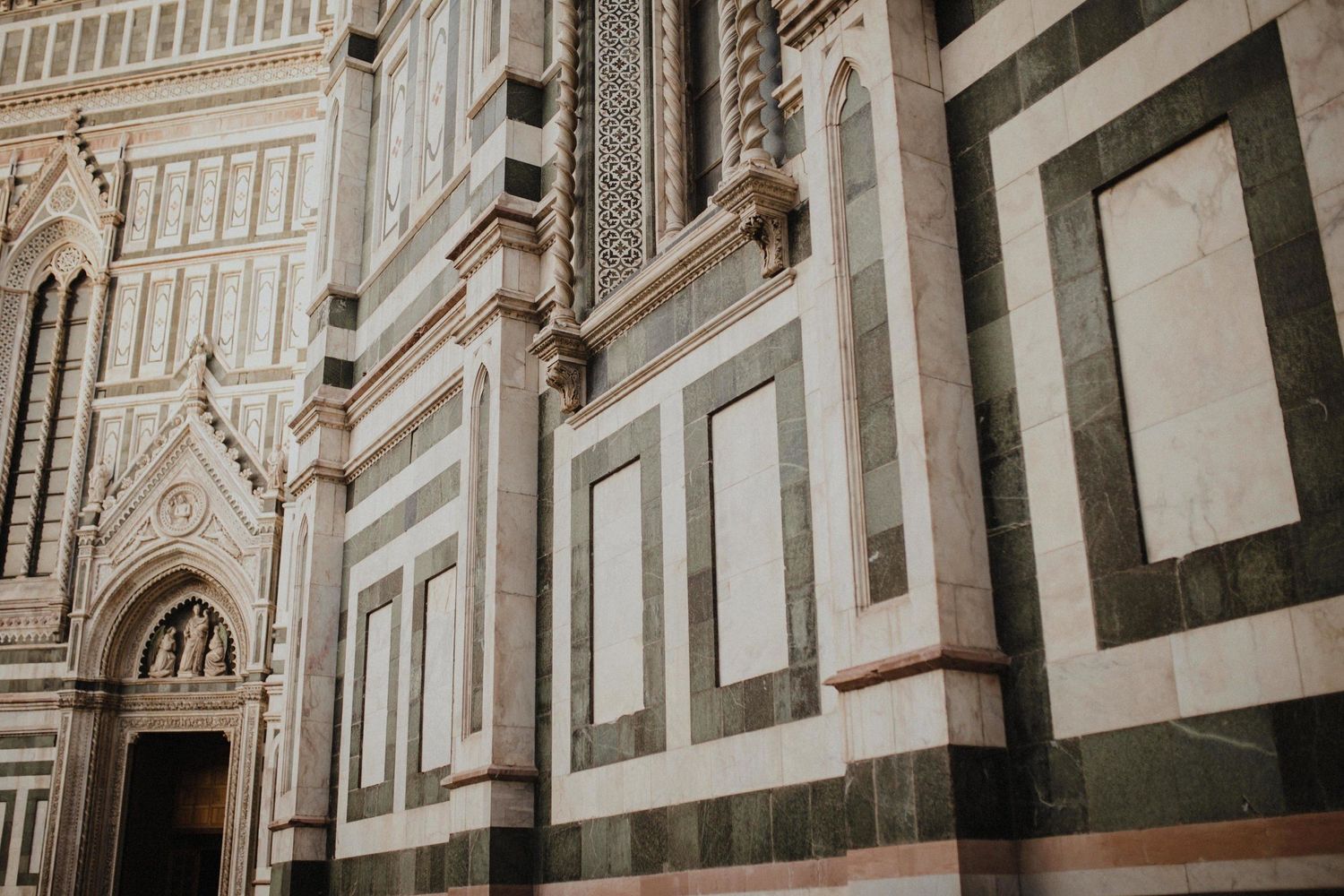 Detailed architectural facade of Florence Cathedral with marble patterns and Gothic elements.