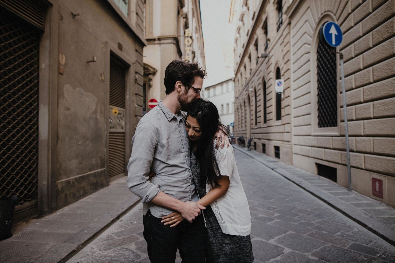 A couple embracing in a narrow European alleyway with historic architecture.