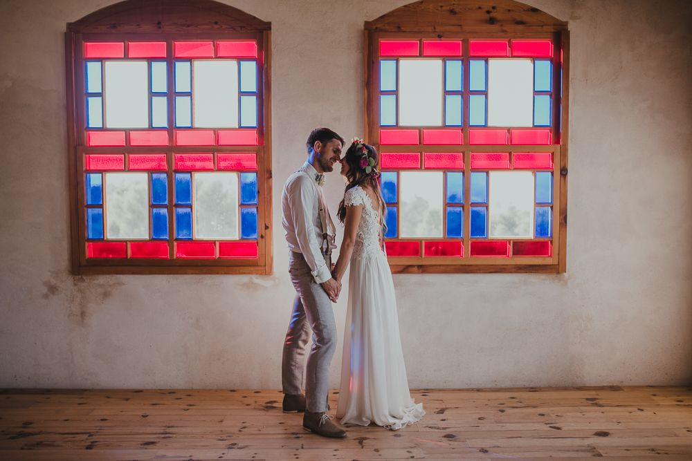 Couple shares intimate moment in rustic venue with red-trimmed windows casting warm light.