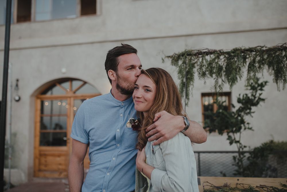 Casual outdoor portrait against white stucco wall with climbing vines.