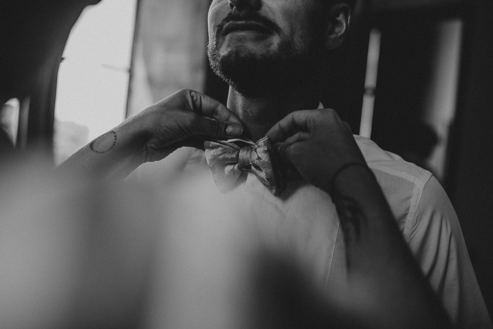 Close-up black and white image of someone adjusting a bowtie.