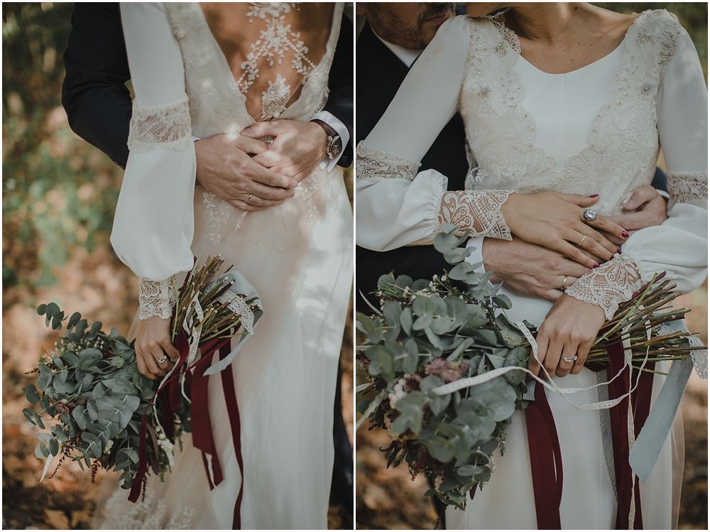 Close-up details of a wedding dress with lace sleeves and eucalyptus bouquet with burgundy ribbons.