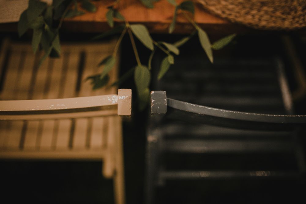 Close-up detail of wedding rings with natural greenery in soft lighting.