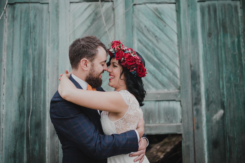 Romantic embrace captured in front of weathered turquoise doors.