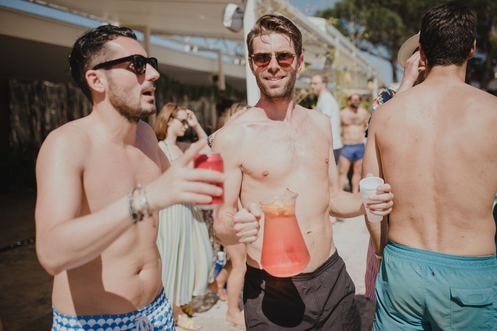 Group enjoying drinks during outdoor pool party on sunny day.