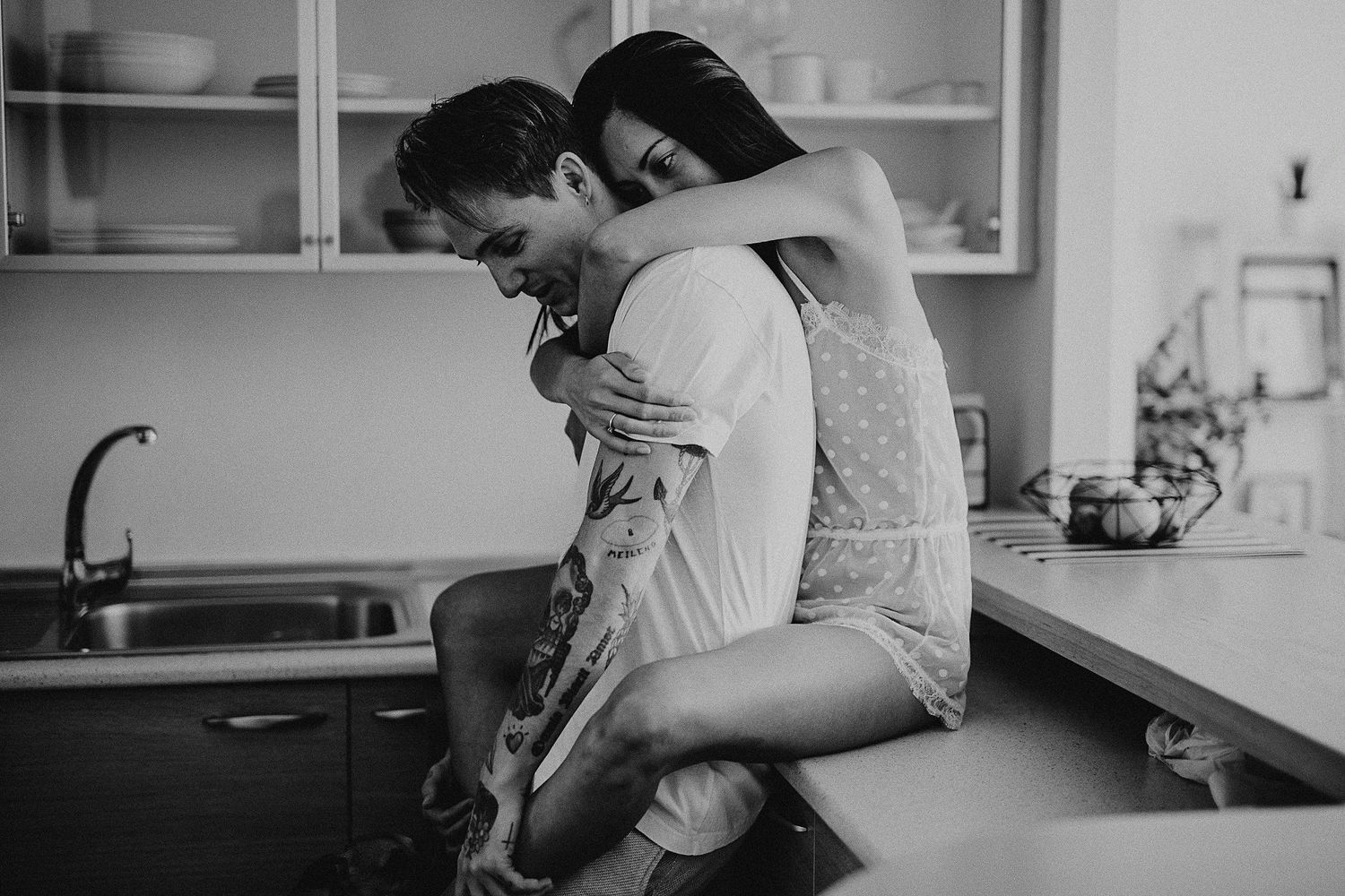 Playful romantic moment between couple in a bright modern kitchen.