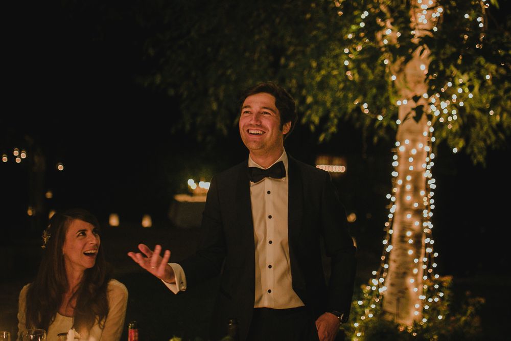 A joyful celebration moment at an evening wedding reception with twinkling lights.