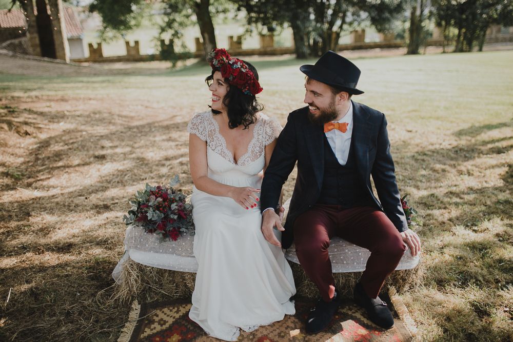 Couple sits on vintage bench in sunlit garden setting.