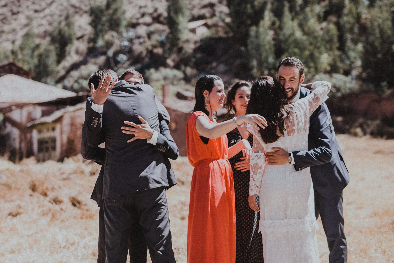 A festive wedding celebration with guests embracing and sharing joyful moments in a scenic mountain setting.