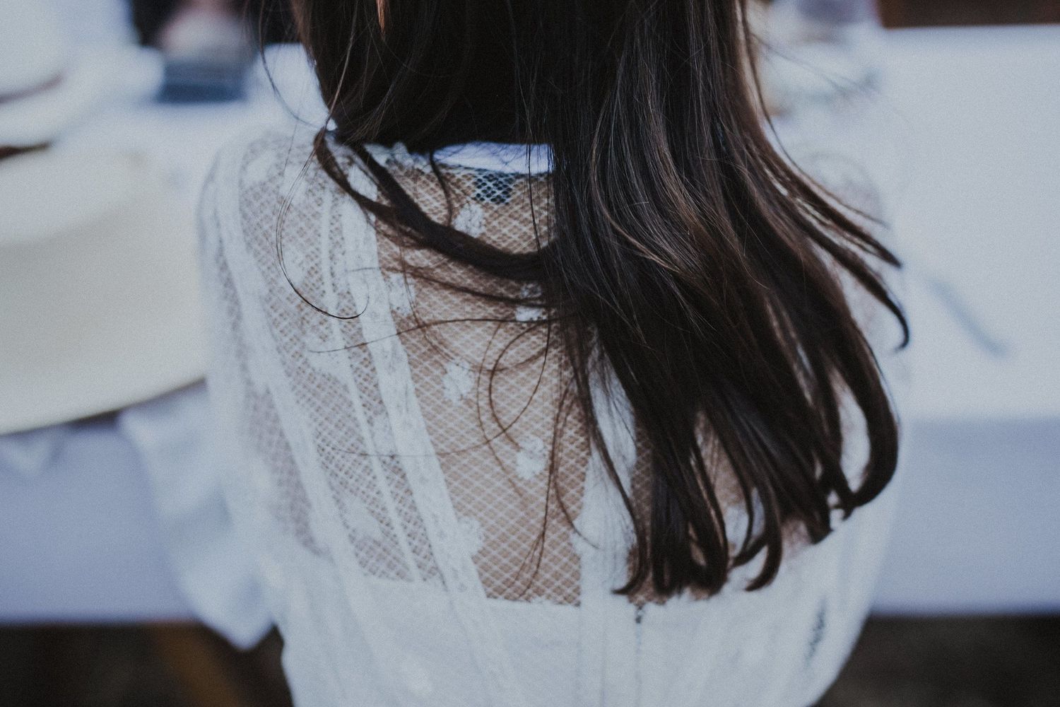 Back view of long dark hair against white lace detail dress.
