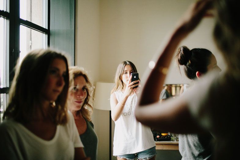 People getting ready by window during wedding preparation.