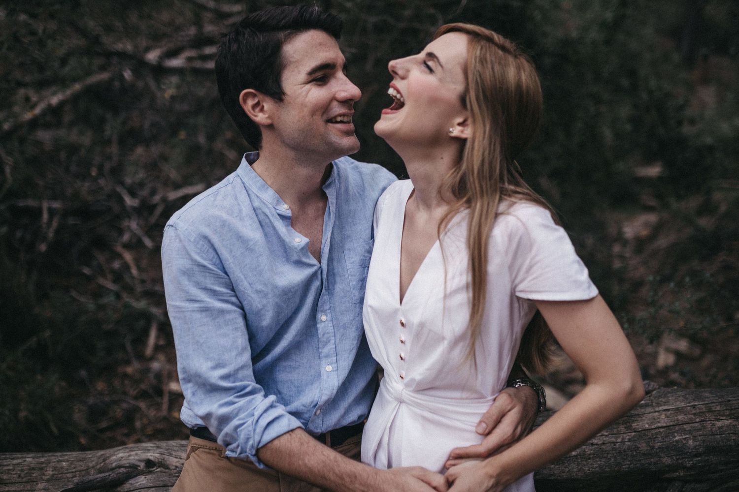Joyful couple sharing laughter while sitting outdoors together.