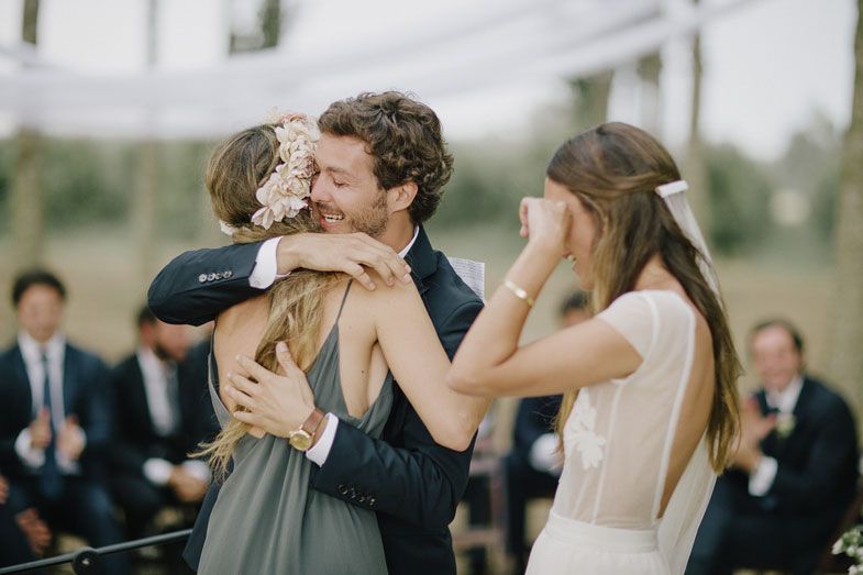 Emotional wedding guests share warm embraces during a heartfelt outdoor celebration.