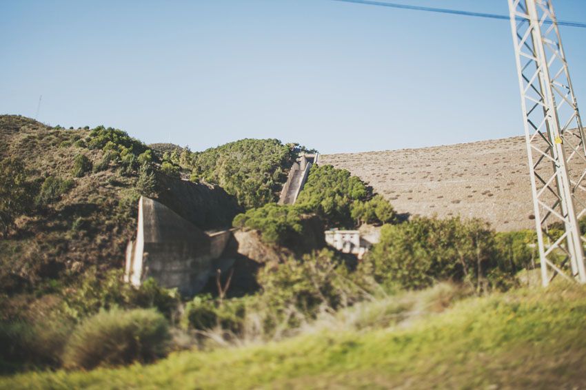 Industrial power lines and structures dot a hillside landscape under blue skies.