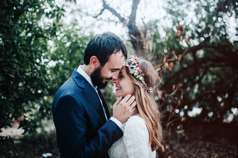 A tender moment between newlyweds surrounded by green foliage and natural light.